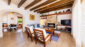 A spacious living area with a fireplace, a television, and a dining area with wooden furniture. - Country House 'Can Simonet' with Private Pool, Wi-Fi and Air Conditioning (Santanyí)
