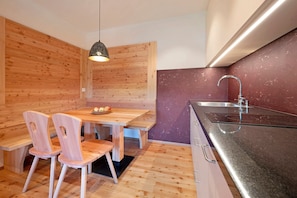 Une cuisine moderne avec des murs en bois, un coin repas avec des chaises, un banc et une suspension.