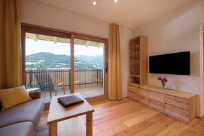 Een woonkamer met een bank, een tafel, een televisie en een houten kast.