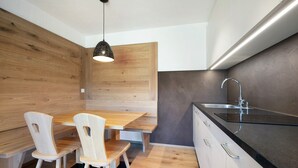 Une cuisine moderne avec un coin repas en bois, un plan de travail noir et un évier en acier inoxydable.