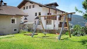 Une maison avec une balançoire dans le jardin, une clôture en bois et une montagne en arrière-plan.