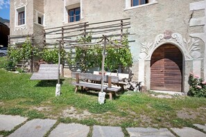 Un bâtiment rustique avec un banc en bois, un sentier en pierre et une porte en bois.