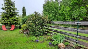 A garden with a wooden fence, red chairs, and various plants.