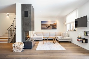 Uma sala de estar moderna com lareira, um conjunto de sofá, uma mesa de centro e uma televisão na parede.