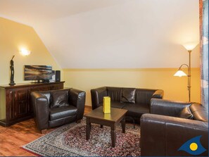 A living room with a sofa, a coffee table, a rug, and a TV on a stand.