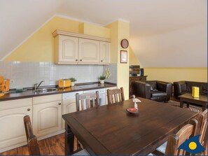A compact kitchen with white cabinets, a dark wooden dining table, and a small dining area with leather seating.