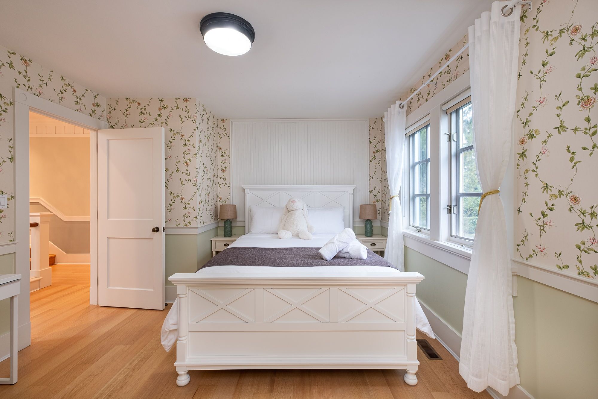 A bedroom with a bed, a nightstand, a lamp, and a window with curtains.