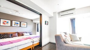 Een moderne hotelkamer met een bed, een slaapbank en een airconditioner.