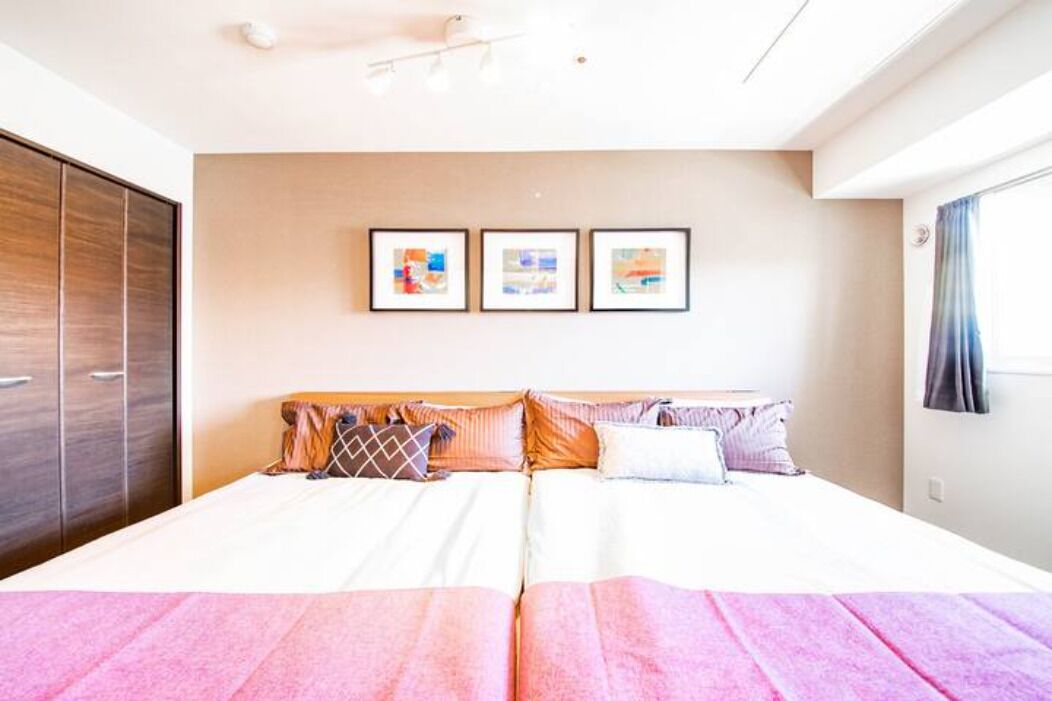 Un lit double avec une tête de lit en bois, une armoire et trois tableaux encadrés accrochés au mur.