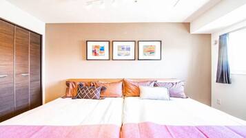 Un lit double avec une tête de lit en bois, une armoire et trois tableaux encadrés accrochés au mur.