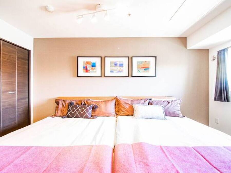 Un lit double avec une tête de lit en bois, une armoire et trois tableaux encadrés accrochés au mur.