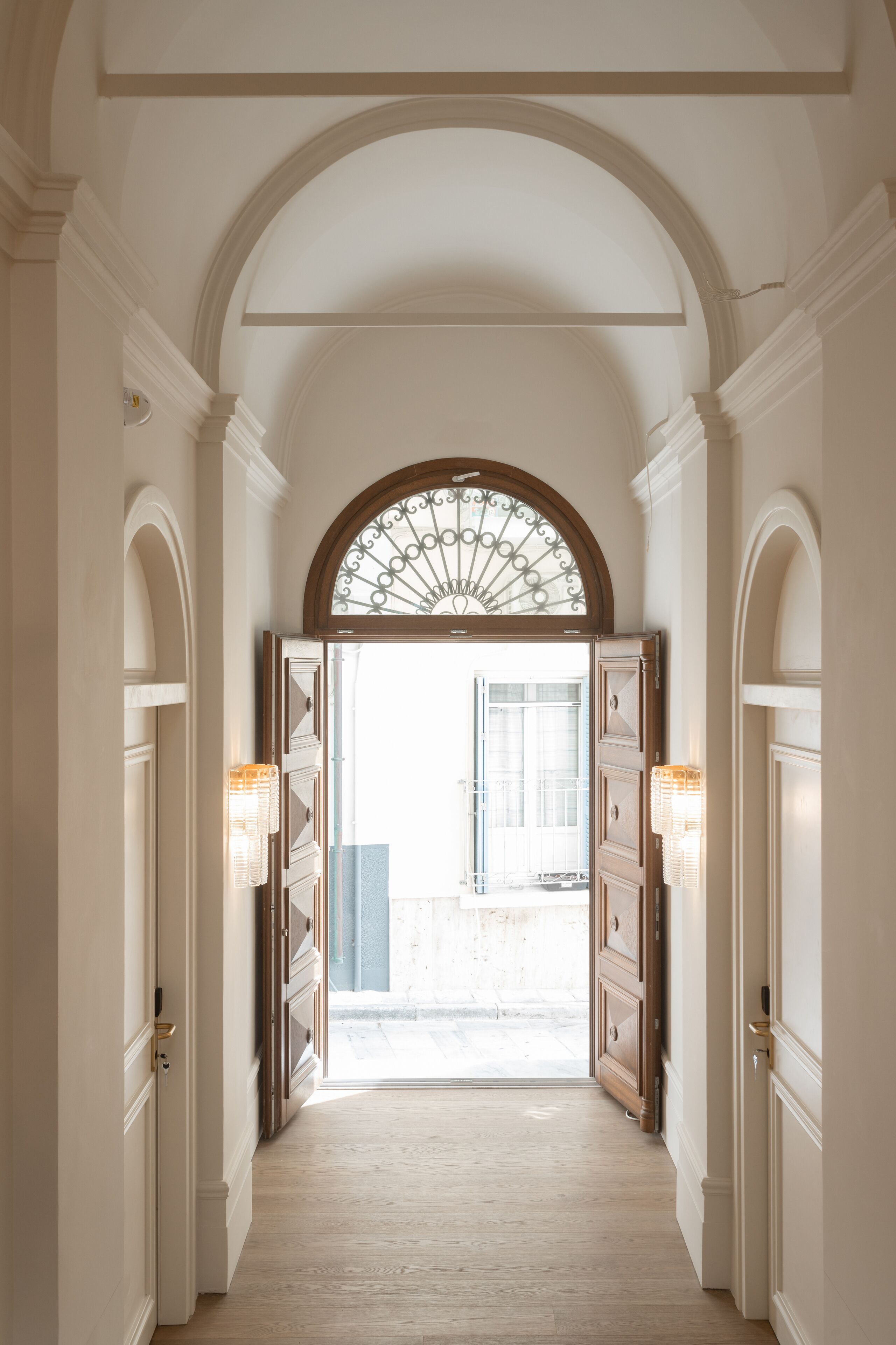 A hallway with a large arched doorway leading to an outdoor area.