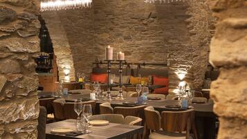 Un restaurante con paredes de piedra, mesas de madera y luces colgantes.