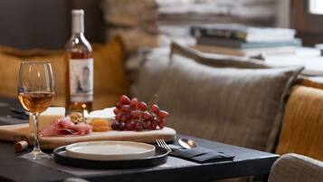 Una mesa con vajilla, uvas, queso y una copa de vino junto a una botella.