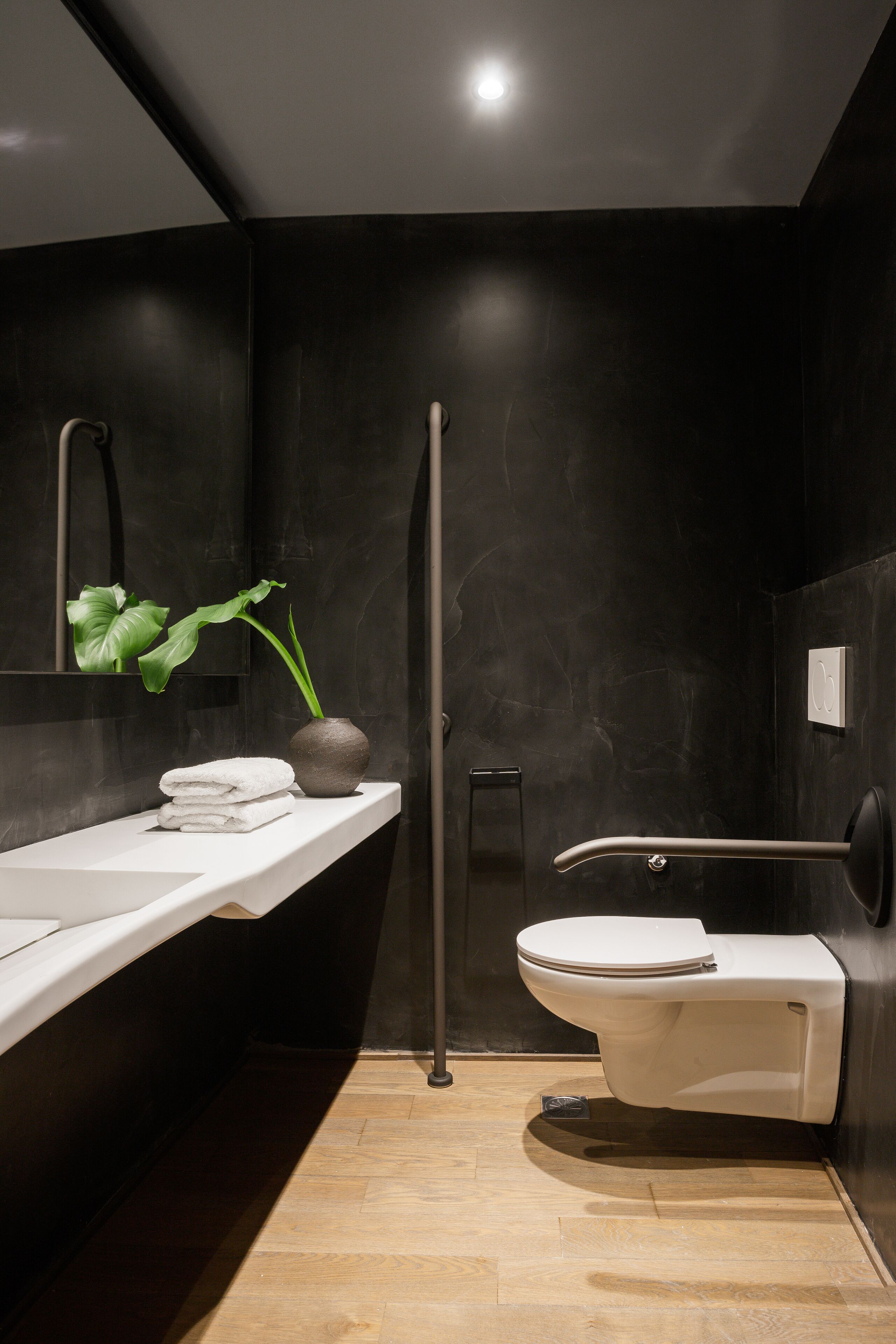 Een moderne badkamer met een wit wastafel, toilet en een plant op het aanrecht.