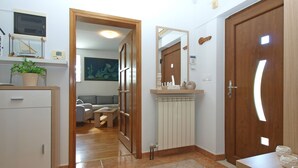 A hallway with a wooden door, a radiator, a small table, and a plant. - House 2087/39057 (Istria - Vinkuran), 500m from the beach (Vinkuran)