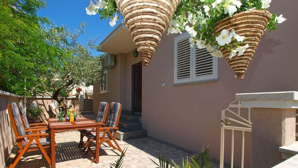 An outdoor patio with a wooden table and chairs, a potted plant, and a hanging basket with white flowers. - House 2087/39057 (Istria - Vinkuran), 500m from the beach (Vinkuran)