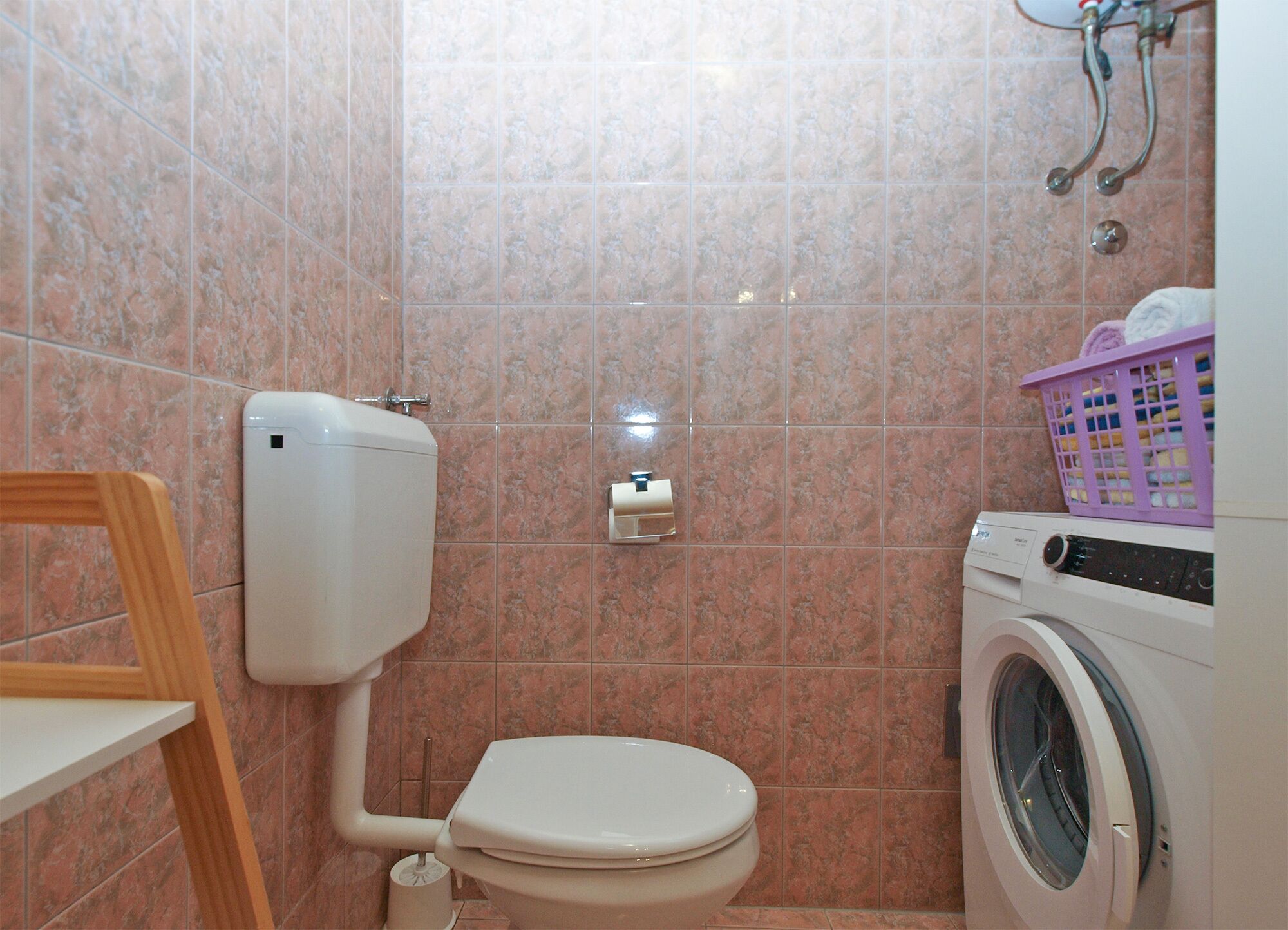 Un baño con inodoro, lavadora y ducha.