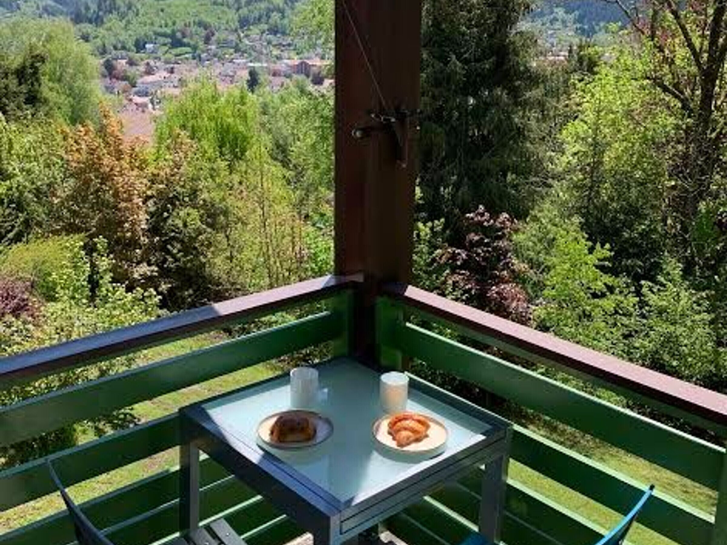 A balcony with a table, two plates with food, and a cup.