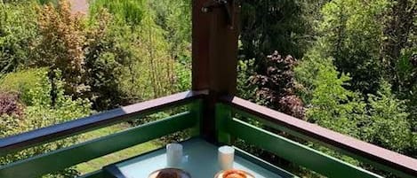 A balcony with a table, two plates with food, and a cup.