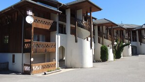 Una hilera de edificios de madera tradicionales con balcones, una escalera central y un cielo despejado.