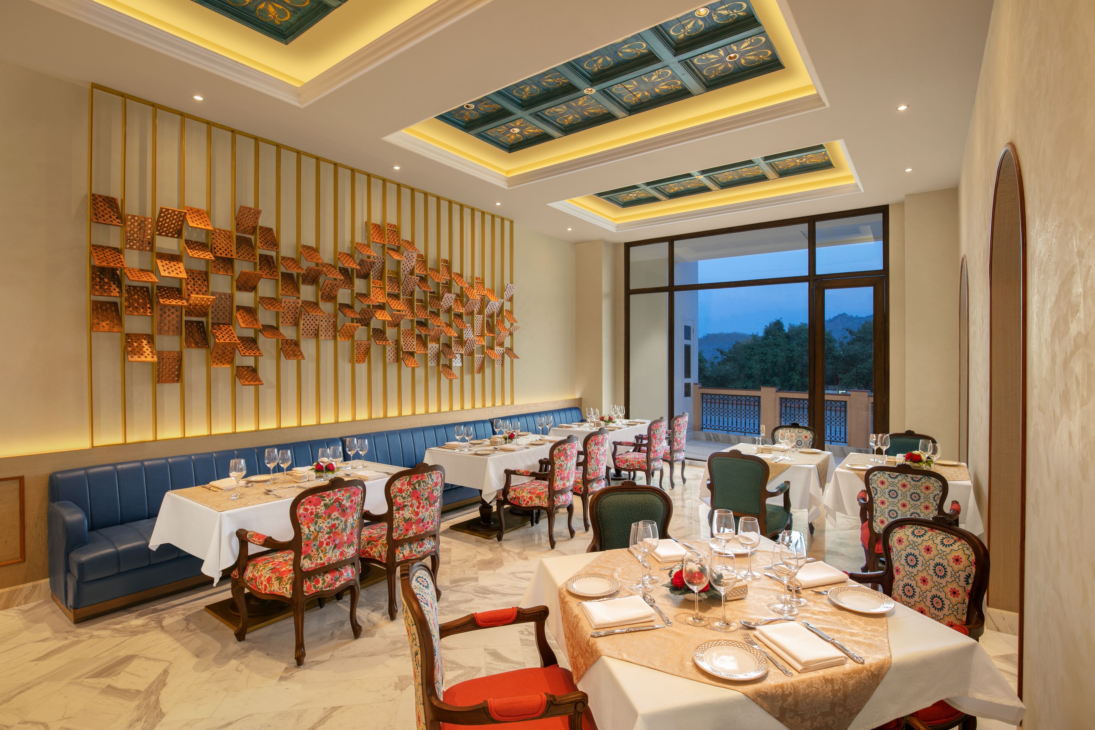 A restaurant with multiple tables and chairs, a decorative wall, and a view of the outdoors.