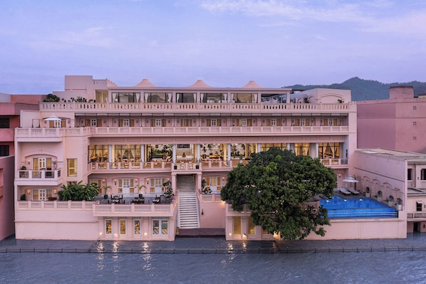 A multi-story hotel with balconies, a swimming pool, and a staircase leading to the upper levels.