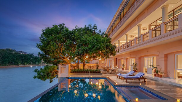 Um hotel luxuoso com uma grande piscina ao ar livre, espreguiçadeiras e uma área de varanda bem iluminada.