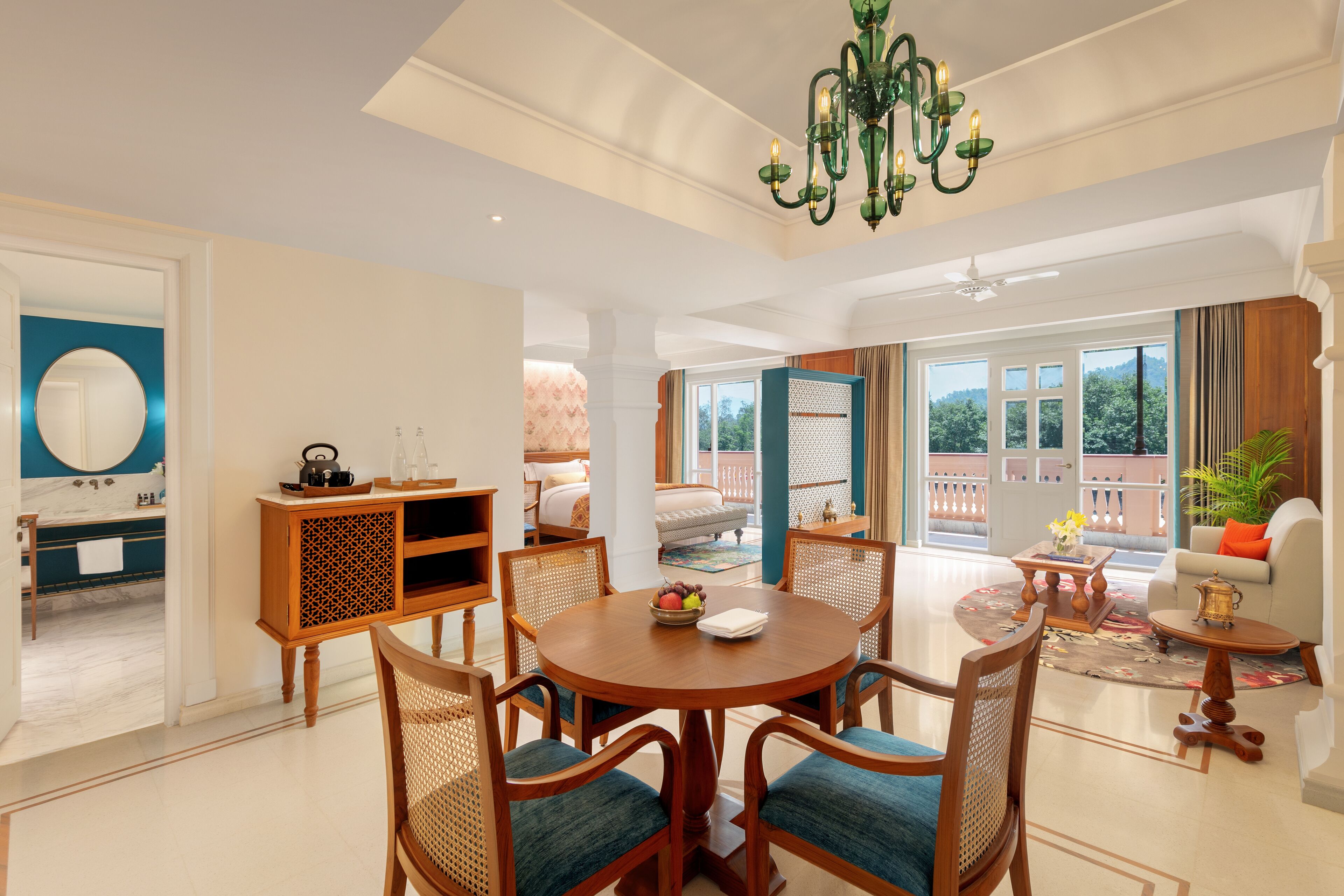 A spacious living area with a round wooden table, comfortable seating, and a chandelier.