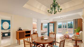 A spacious living area with a round wooden table, comfortable seating, and a chandelier.