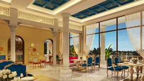 Uma sala de jantar espaçosa, com pé direito alto, grandes janelas e detalhes decorativos no teto.