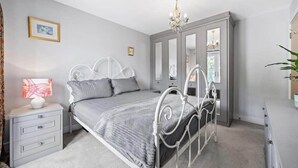 Ein Schlafzimmer mit Bett, Nachttisch, Kommode und Spiegel.