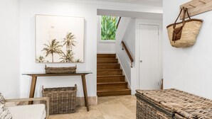 A staircase with wooden steps leading to a door, a wicker basket on the floor, and a wicker bench in the foreground.