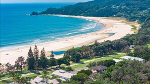 A coastal resort with a beachfront, lush greenery, and residential buildings.