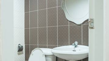 A bathroom with a white toilet, a white sink, and a mirror above the sink. The walls are tiled with a brown pattern.