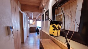 A hallway with wooden floors, a wooden bench, a telephone, and a hanging decorative item. - Spacious apartment in village center with parking (Les Gets)