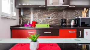 Une cuisine moderne avec des meubles de couleur sombre, un pare-feu en marbre et un plan de travail rouge.