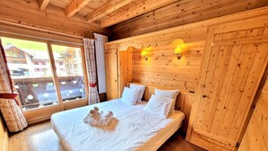 Um quarto de madeira com uma cama, duas luminárias na parede e uma janela com cortinas.