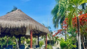 A clear blue pool with a thatched-roof structure and palm trees in the background. - Beautiful 2 Bdrs Villa with Pool,Private Beach,Wi-Fi, Kayaks, Manager, Chef . (Playa del Carmen)