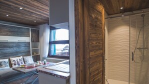 Et moderne badeværelse med glasvæg omkring bruseområdet og træloft.