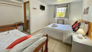 Habitación de hotel con dos camas, un escritorio pequeño, un televisor y una ventana con cortinas.
