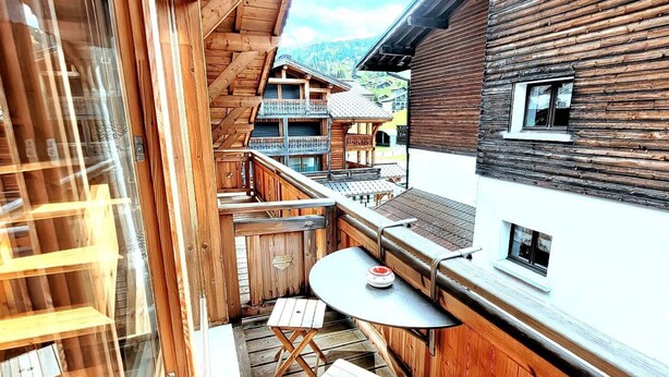A wooden balcony with a table and chairs, overlooking a mountainous area. - Cozy chalet in Les Gets center, 4-5 ppl, balcony, garage (Les Gets)