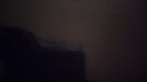 A dimly lit room with a large bed and a nightstand. - Blank Blank Blank Blank (Port Morant)