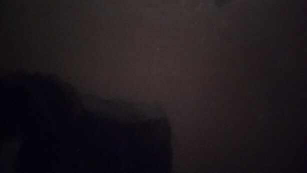 A dark room with a visible window and a partial view of a bed. - Blank Blank Blank Blank (Port Morant)