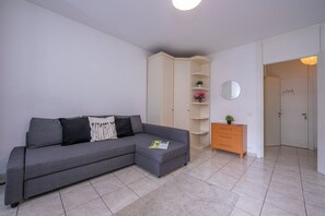 Un salon moderne avec un canapé d’angle gris, un meuble en bois et une petite commode en bois.