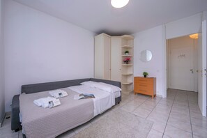 Une chambre à coucher comprenant un lit, une commode, une armoire et une porte donnant sur une autre pièce.