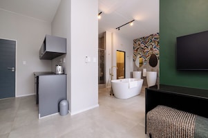 A modern bathroom with a freestanding bathtub, a vanity with a mirror, and a shower area.