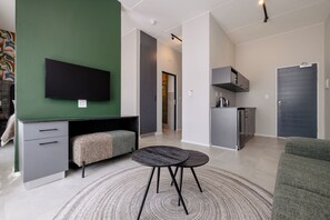 A modern living space with a flat-screen TV, a sofa, a dining table, and a kitchen area. - MINT Express Melrose View (Johannesburg)