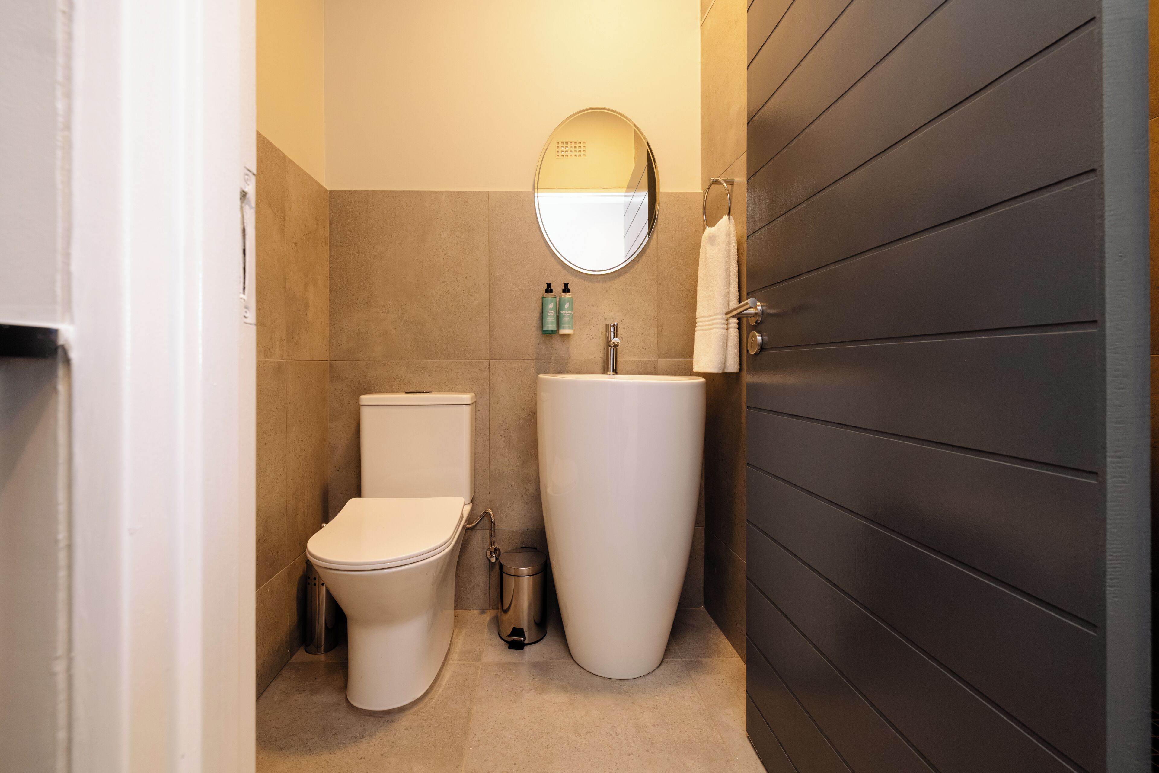 A bathroom with a toilet, sink, and mirror.