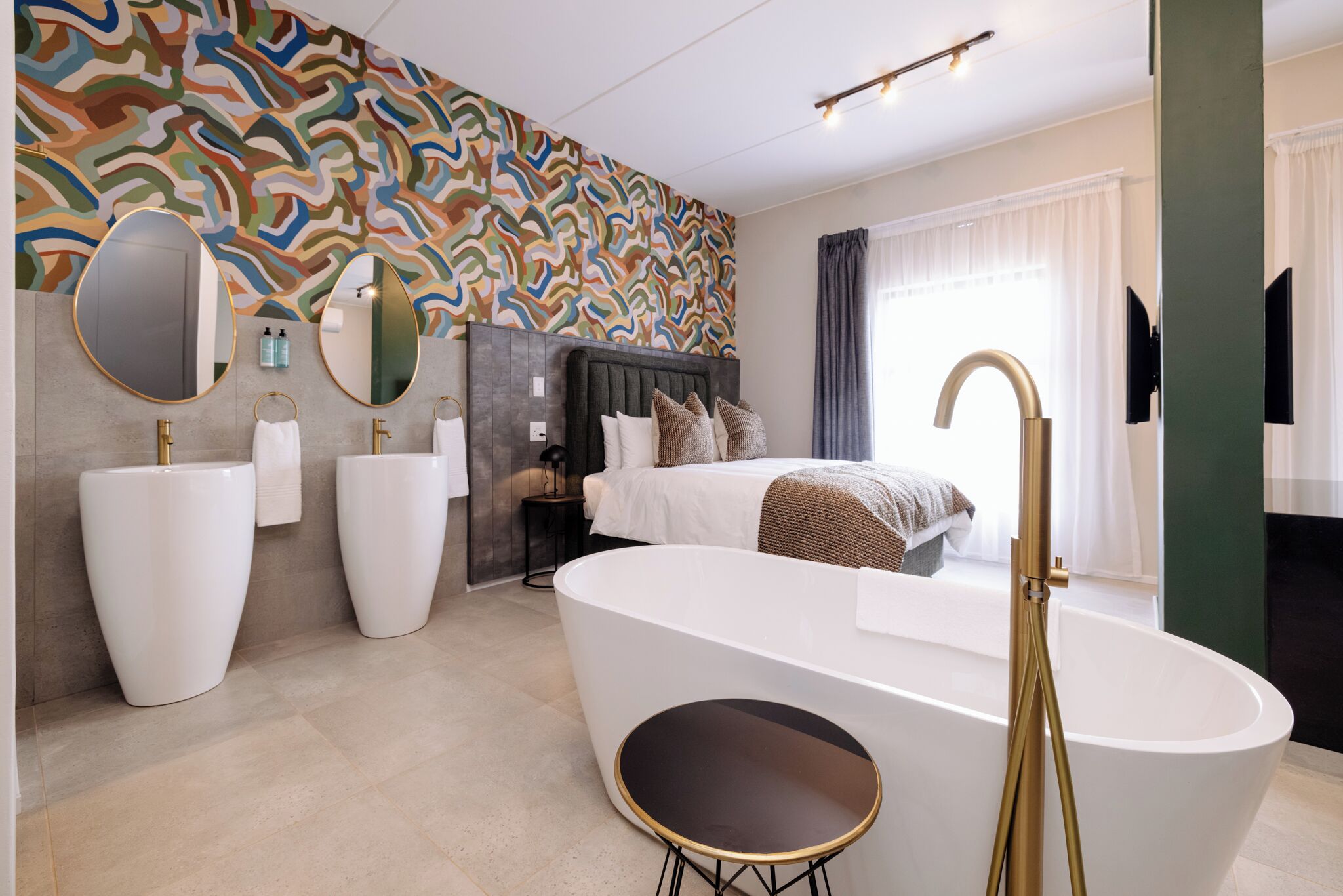 A modern bathroom with a freestanding bathtub, a large mirror, and a patterned wall.
